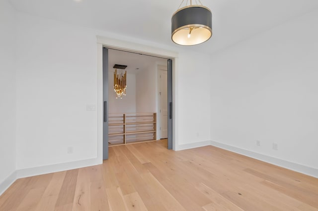 unfurnished room with light wood-type flooring and a notable chandelier