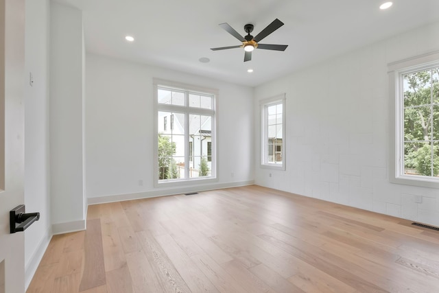 unfurnished room with a wealth of natural light, light hardwood / wood-style floors, and ceiling fan