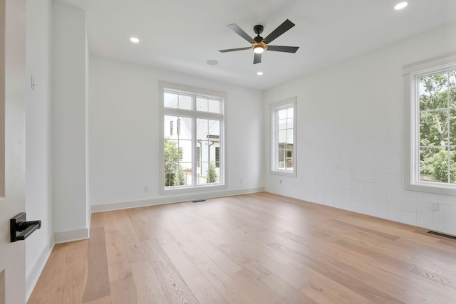 empty room featuring light wood-type flooring, visible vents, and a healthy amount of sunlight