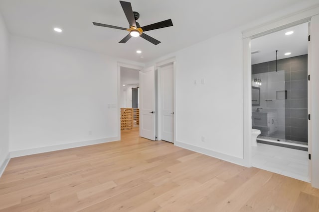 unfurnished bedroom with ceiling fan, ensuite bath, and light hardwood / wood-style floors