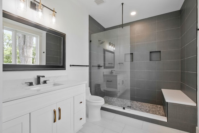 bathroom featuring toilet, a tile shower, vanity, and tile patterned floors