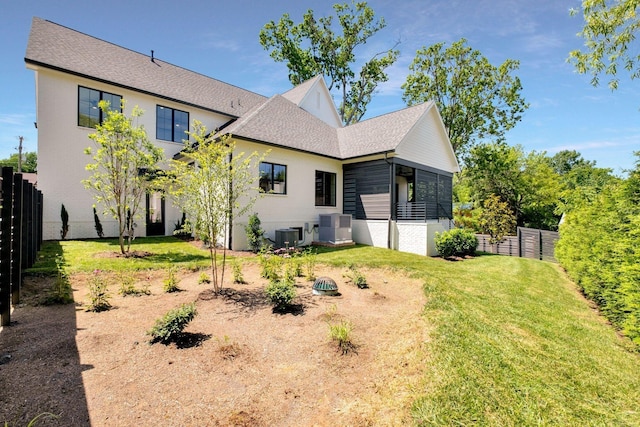 back of house with a fenced backyard, central AC unit, and a yard