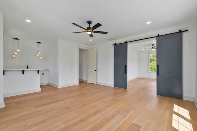 interior space with ceiling fan, light hardwood / wood-style floors, and a barn door