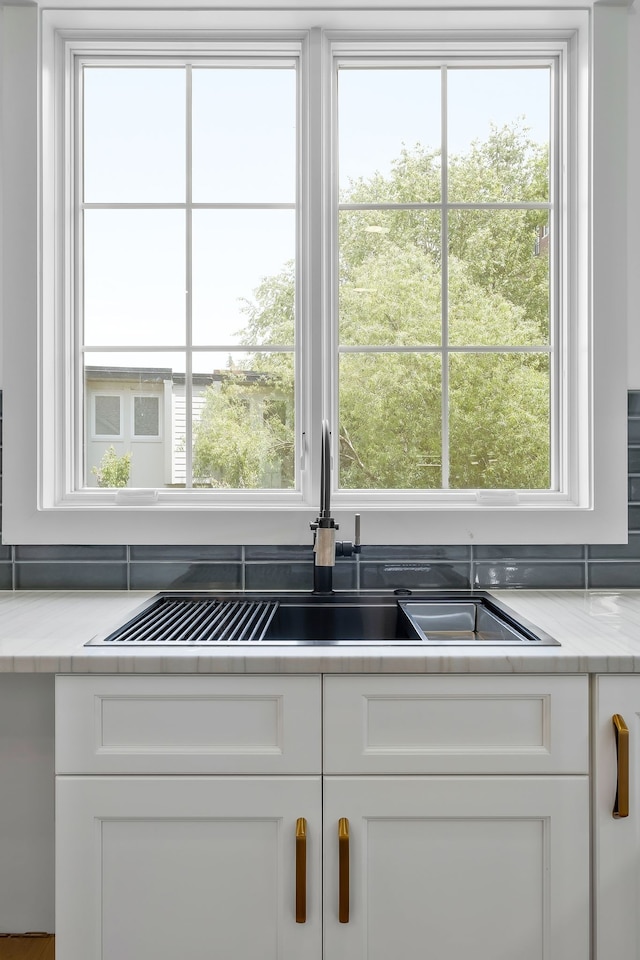 kitchen featuring white cabinets, sink, and light stone countertops