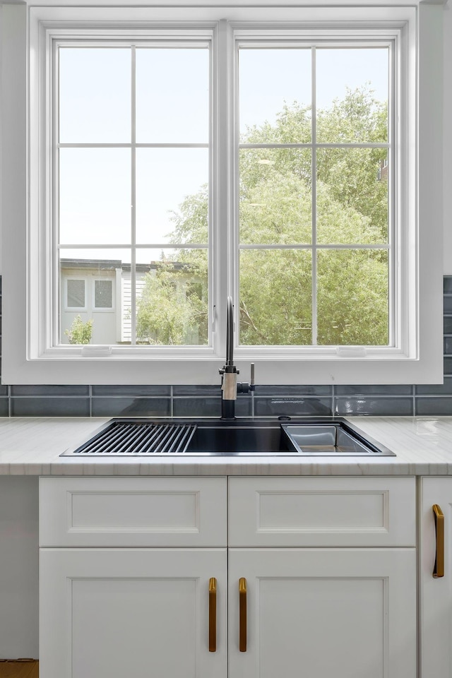 kitchen featuring white cabinetry, a sink, and light stone countertops