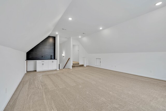 bonus room with light colored carpet and lofted ceiling