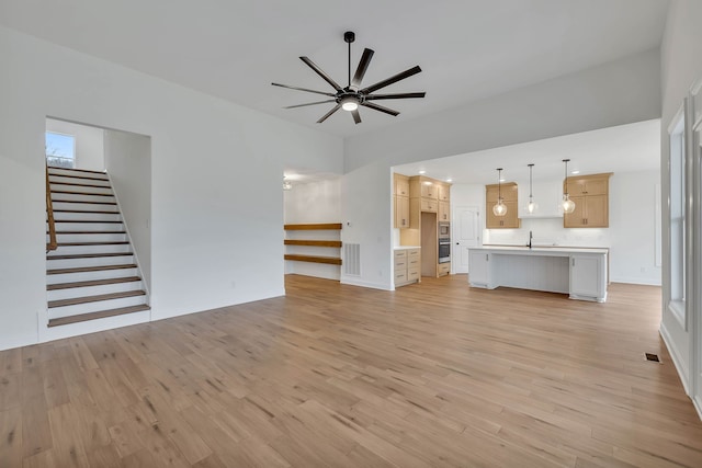 unfurnished living room featuring ceiling fan, sink, and light hardwood / wood-style flooring