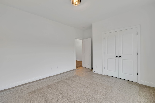 unfurnished bedroom featuring light carpet and a closet