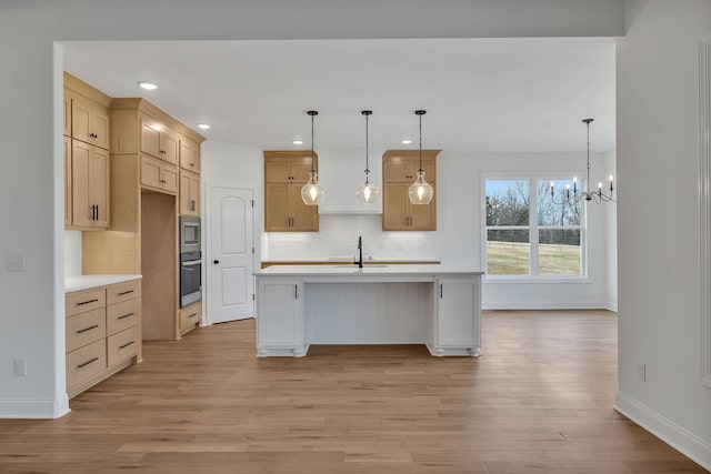 kitchen with a center island with sink, a chandelier, light wood-type flooring, and appliances with stainless steel finishes