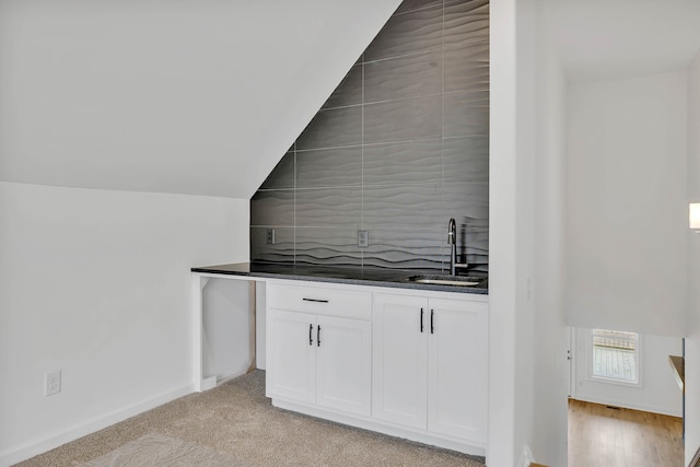 bar with white cabinetry, sink, light carpet, and lofted ceiling