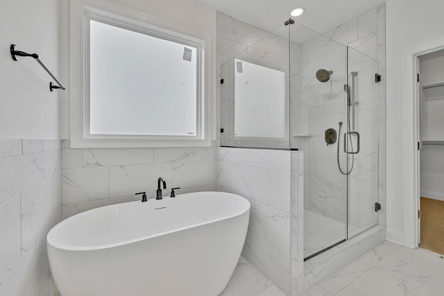 bathroom featuring shower with separate bathtub and tile walls