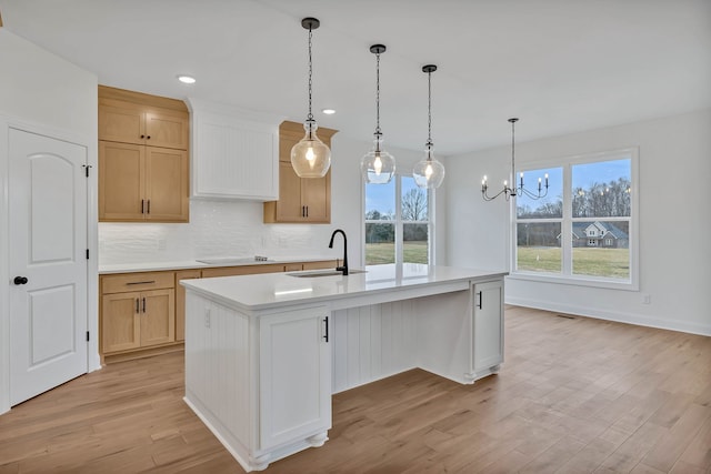 kitchen with a center island with sink, light hardwood / wood-style floors, sink, and a wealth of natural light