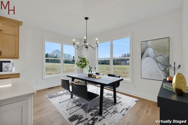 dining space featuring light hardwood / wood-style floors and an inviting chandelier