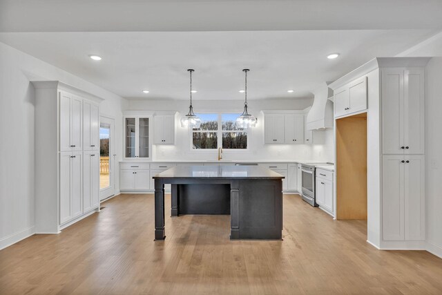 kitchen featuring white cabinets, electric range, light hardwood / wood-style floors, and a kitchen island