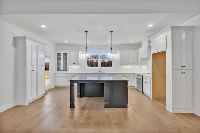 kitchen with white cabinets, a kitchen island, electric stove, and custom range hood