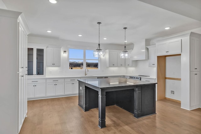 kitchen featuring a sink, light wood-type flooring, white cabinets, and custom range hood