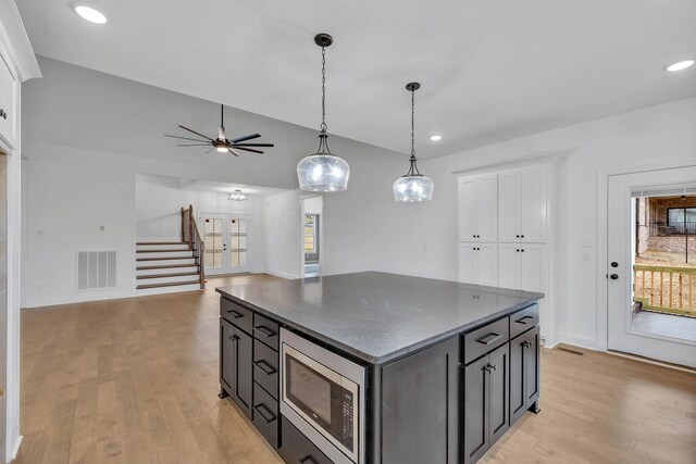 kitchen featuring white cabinets, a wealth of natural light, a kitchen island, and stainless steel microwave