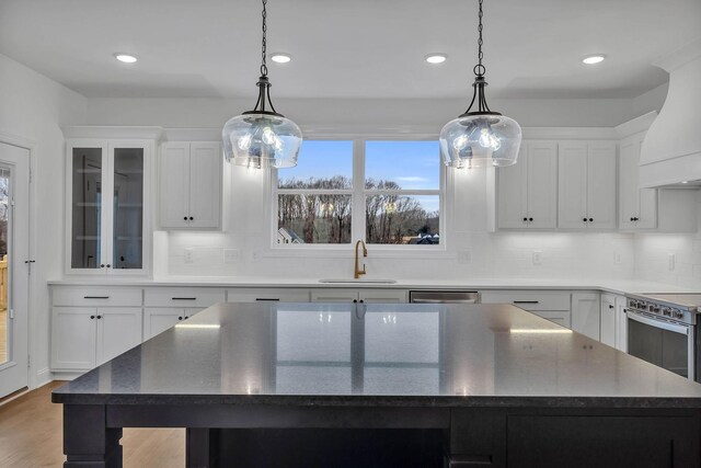 kitchen with pendant lighting, a kitchen island, white cabinetry, and sink