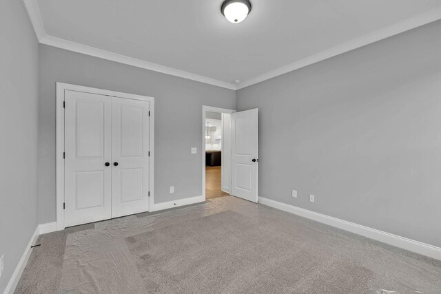 unfurnished bedroom with light carpet, a closet, and ornamental molding