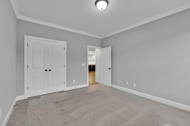 unfurnished bedroom featuring a closet, baseboards, ornamental molding, and carpet flooring