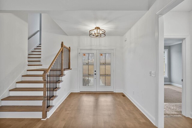 entryway featuring french doors, a chandelier, and light hardwood / wood-style flooring