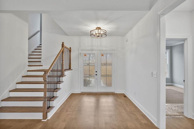 entrance foyer featuring wood finished floors, baseboards, stairs, french doors, and a notable chandelier