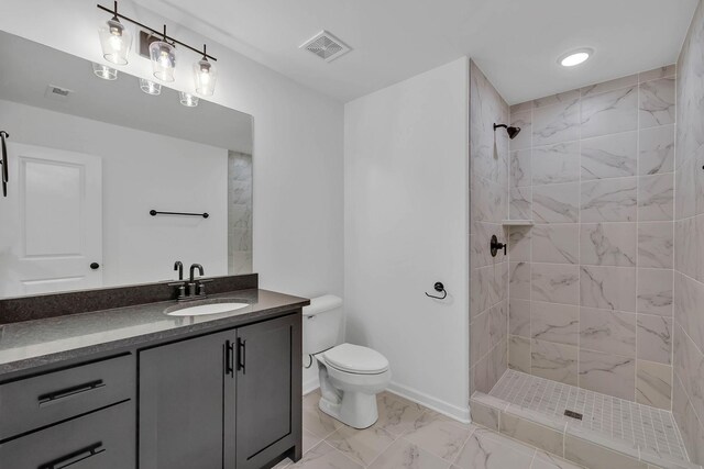 bathroom featuring a tile shower, vanity, and toilet