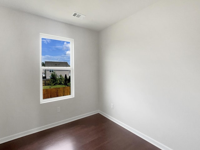 empty room featuring visible vents, dark wood finished floors, and baseboards