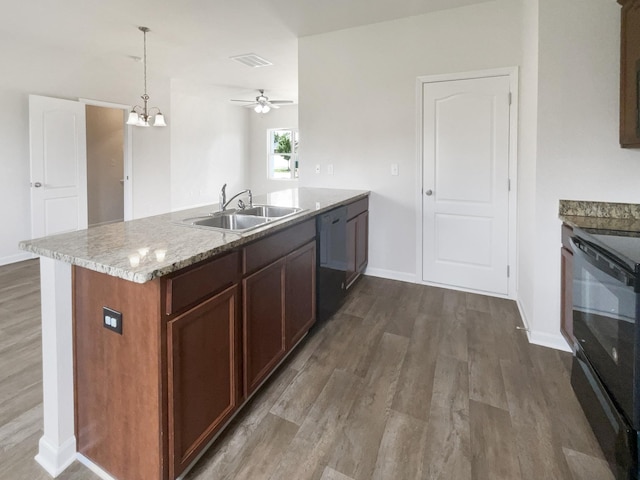 kitchen with dark wood-style floors, hanging light fixtures, a sink, light stone countertops, and black appliances