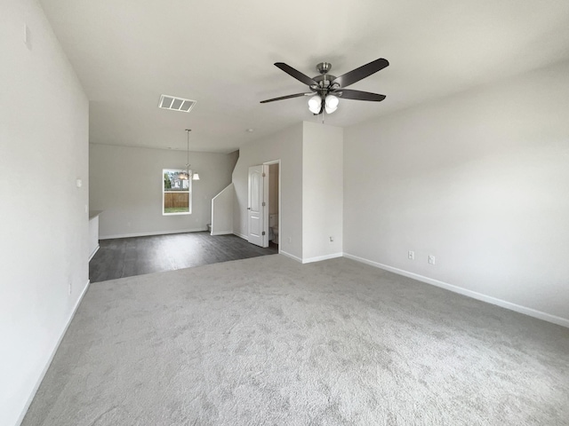 empty room with baseboards, visible vents, dark colored carpet, and a ceiling fan