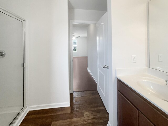 bathroom featuring a stall shower, wood finished floors, vanity, and baseboards