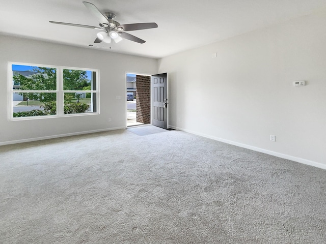 spare room with light colored carpet, ceiling fan, and baseboards