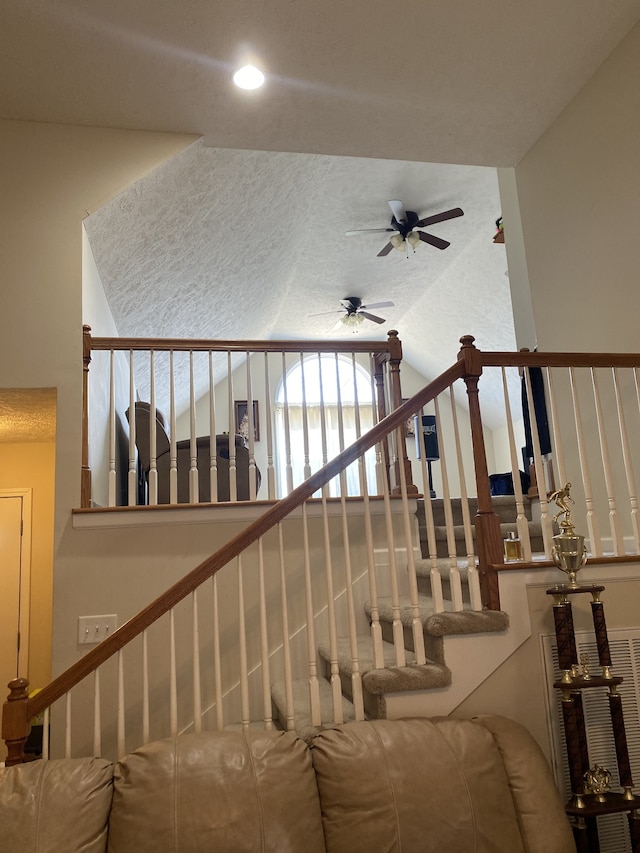 stairway featuring ceiling fan, lofted ceiling, and a textured ceiling