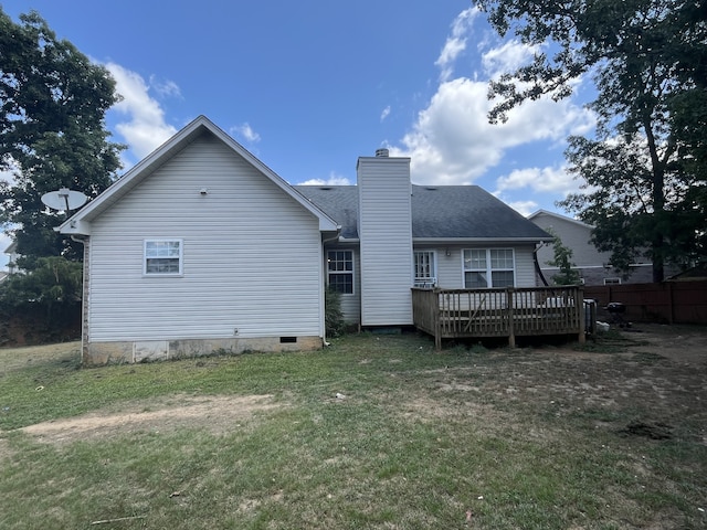 rear view of house with a wooden deck and a lawn