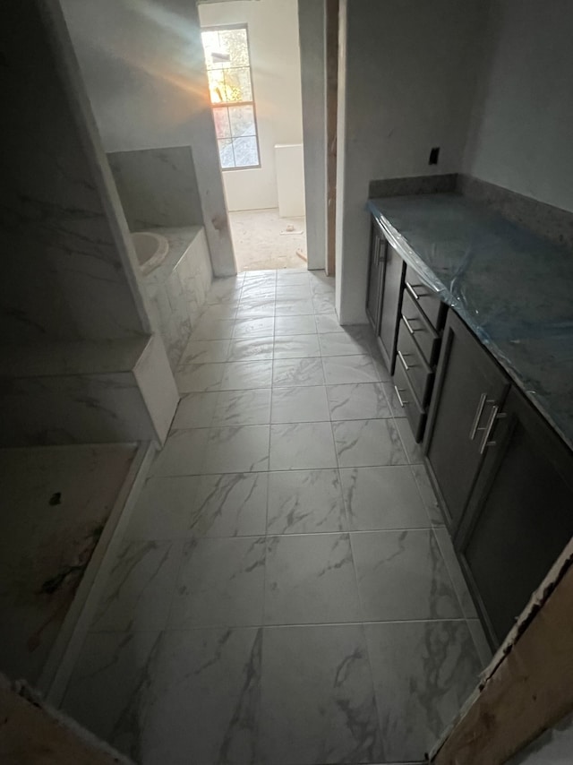 bathroom featuring marble finish floor and a bath