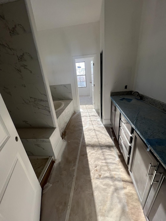 bathroom featuring a sink, double vanity, and a garden tub