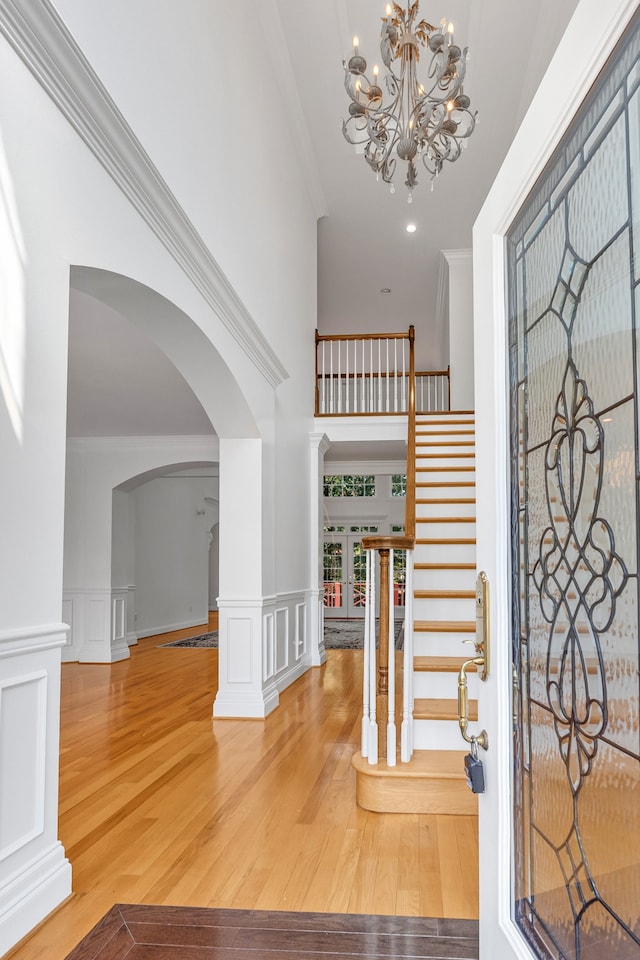 entryway with stairs, a decorative wall, wood finished floors, and crown molding