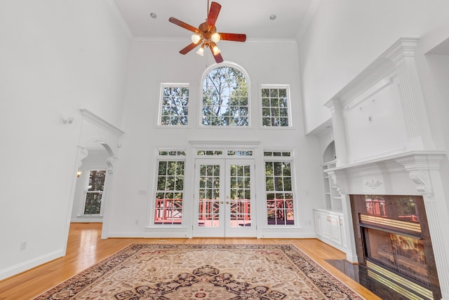 interior space with a high end fireplace, light wood-type flooring, crown molding, and ceiling fan