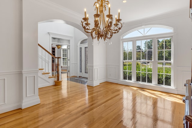 interior space with ornamental molding, a notable chandelier, and light hardwood / wood-style flooring