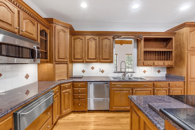 kitchen featuring brown cabinets, light wood-style flooring, stainless steel appliances, and a sink