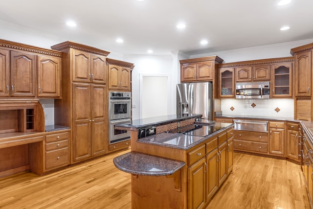 kitchen featuring brown cabinets, appliances with stainless steel finishes, glass insert cabinets, a kitchen island, and dark stone countertops