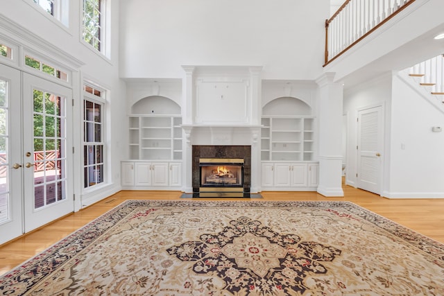 living room featuring a high ceiling, built in shelves, and light hardwood / wood-style flooring