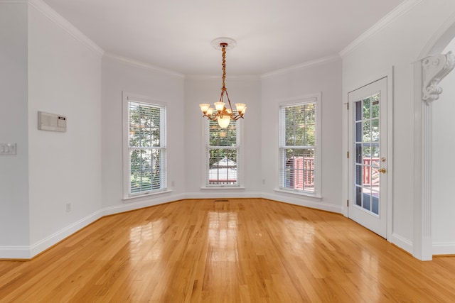 unfurnished dining area featuring light wood-type flooring, a notable chandelier, crown molding, and a healthy amount of sunlight