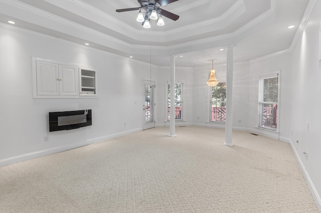 unfurnished living room with light carpet, ornate columns, a tray ceiling, ceiling fan, and ornamental molding