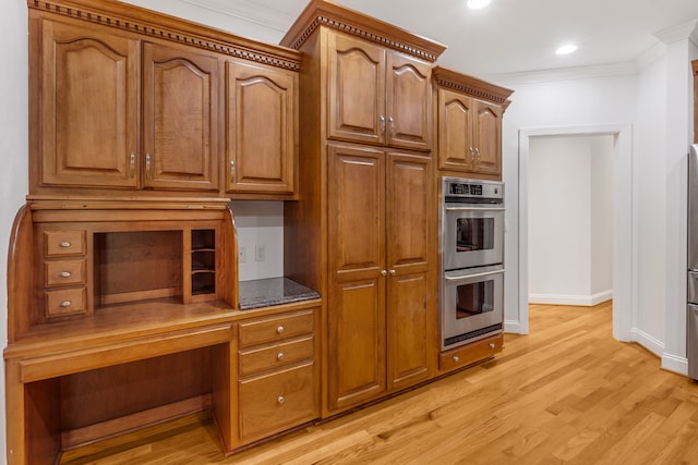 kitchen with double oven, brown cabinetry, light wood-style flooring, and crown molding