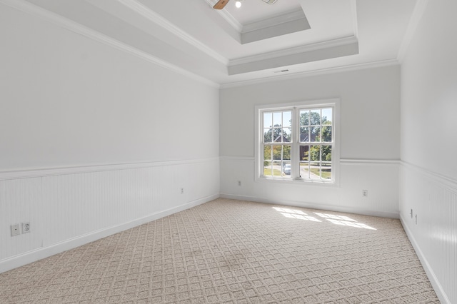 empty room featuring ceiling fan, light colored carpet, a raised ceiling, and ornamental molding