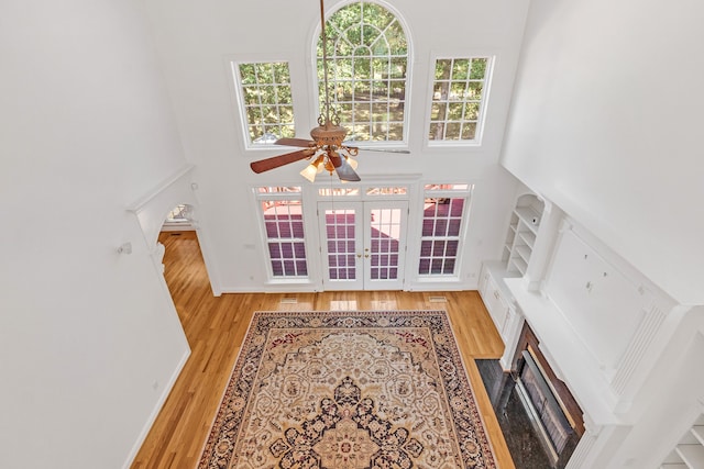 living room featuring a high ceiling, ceiling fan, and light hardwood / wood-style flooring