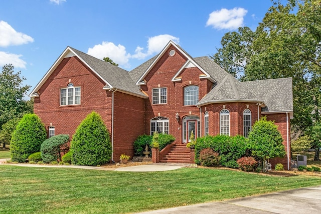 traditional-style home featuring a shingled roof, a front yard, and brick siding