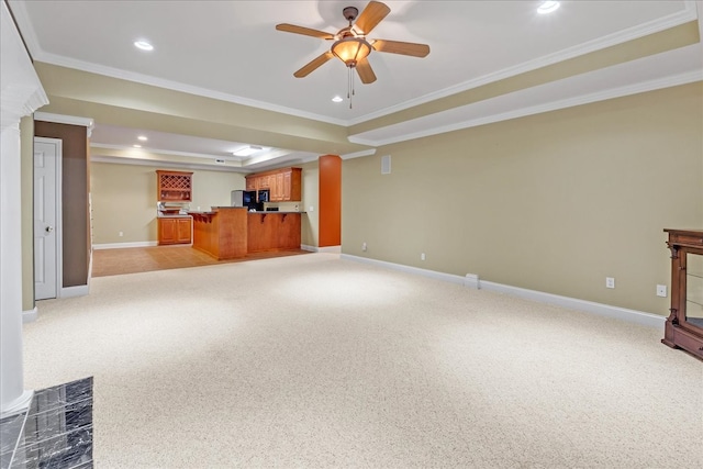 unfurnished living room with a tray ceiling, ornamental molding, carpet, and ceiling fan