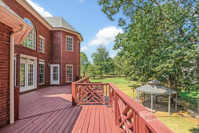 wooden deck featuring french doors, a lawn, and a gazebo